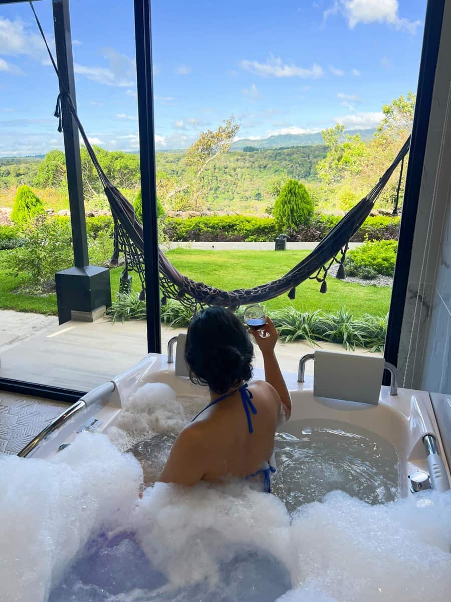 Jacuzzi con burbujas frente a un ventanal con vista al jardín y la montaña