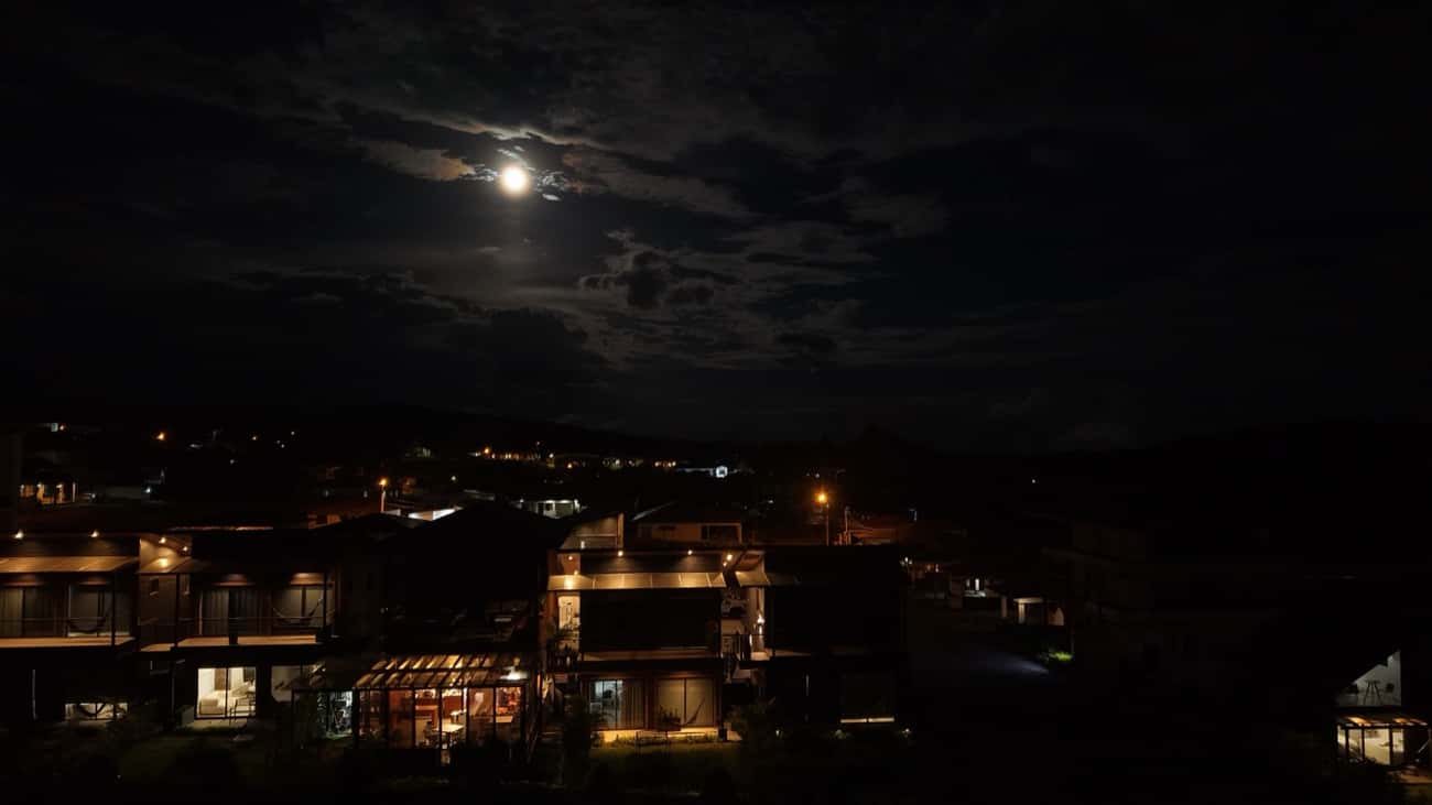 El complejo Sunset iluminado de noche bajo la luna, con el pueblo de Boquete al fondo
